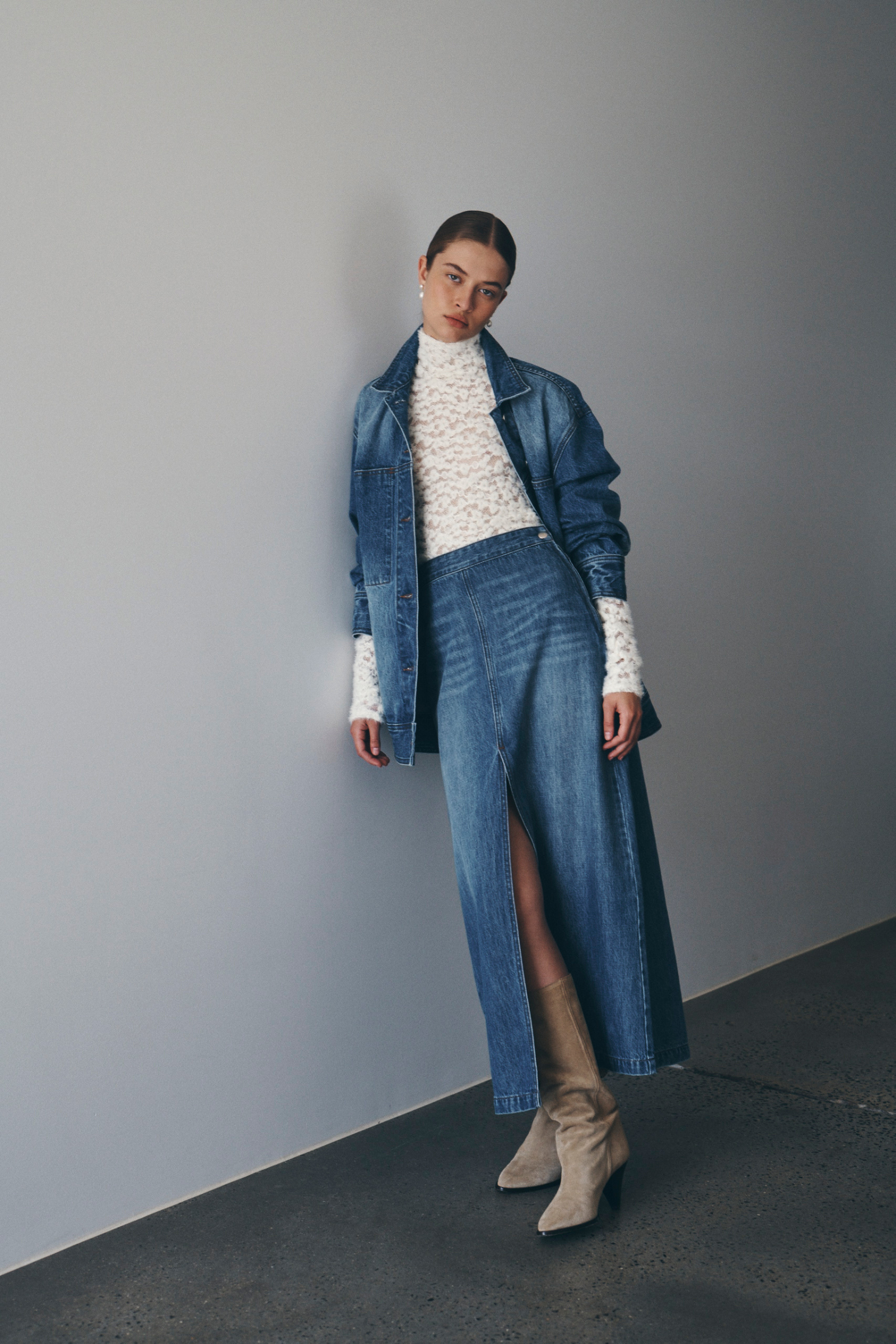 Bianca wears the Iko Relaxed Denim Jacket, Valerie Hemp Midi Skirt, and Galo Lace Fuzzy Top in Creme. All pieces are from ROWIE The Label’s Autumn / Winter ’24 Collection. Bianca styles the look with brown suede knee-high boots.