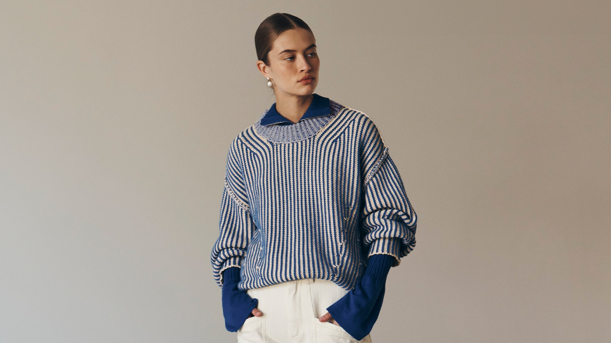 Bianca wears the Tish Knit Jumper in Cobalt over the Travis Zip Knit Top in Cobalt paired with the Gio Jeans in Cream. She accessorises with pearl drop earrings and completes the look with a low, slick bun. 